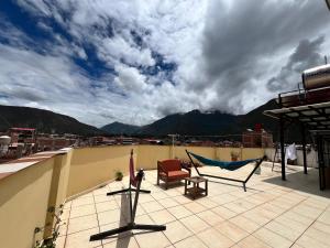 a patio with a hammock and chairs on a roof at Refugio del Valle del Sol in Urubamba