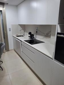 a kitchen with white cabinets and a black sink at Casa la Pluma Torrevieja in Torrevieja +2 photos