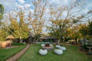 a yard with a park with a bench and trees at Sundown Lodge and Confrence in Aliwal North