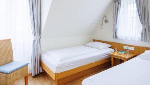 a small room with two beds and a chair at Hapimag Resort Dünenblick in Westerland +20 photos