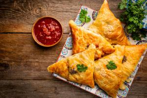 a plate of food with empanadas on a wooden table at hotel mon ville alkapuri in Vadodara