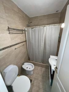 a bathroom with a white toilet and a sink at Departamento duplex Pinamar in Pinamar +9 photos
