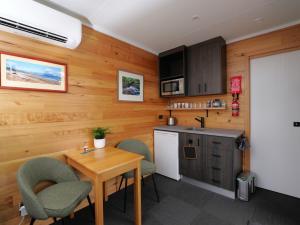 a kitchen with wooden walls and a table and chairs at Leven Studio - StayTiny at Ulverstone in Ulverstone