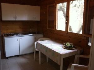 a kitchen with a table and a stove and a window at Chalet Pineta Mare in Foce Varano