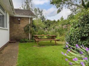 a wooden picnic table in a yard with flowers at 3 Bed in Sheringham oc-86262 in Sheringham