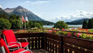 a balcony with chairs and flowers and a view of the mountains at Hotel Seehof direkt am Heidsee in Valbella