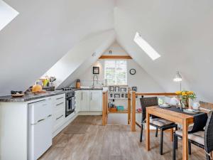 a kitchen with white cabinets and a table and chairs at 1 Bed in North Walsham oc-48723 in Bacton +3 photos