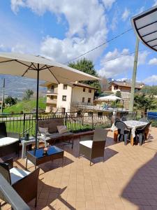 a patio with chairs and tables and an umbrella at Casa Fiocco vista Lago in Pisogne