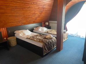 two twin beds in a room with a wooden ceiling at Karikás Apartman in Hajdúszoboszló +3 photos