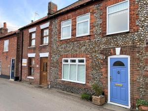a brick house with a blue door on a street at 2 Bed in Melton Constable oc-91371 in Briston