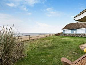 a yard with a fence and a house and the ocean at 2 Bed in Norwich oc-75391 in Bacton