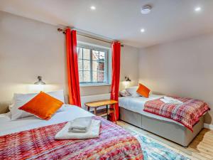 a bedroom with two beds and a window with red curtains at 3 Bed in Colchester oc-94016 in Dedham