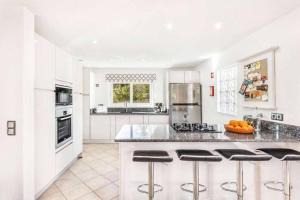 a kitchen with white cabinets and a island with bar stools at Casa Jardim in Loulé