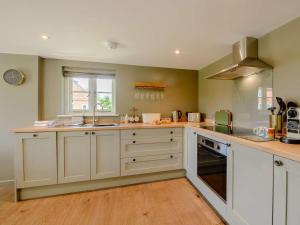 a large kitchen with white cabinets and a window at 1 Bed in Battle oc-88029 in Brightling