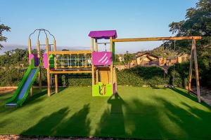 a playground with two swings on a green lawn at Flower Camping de L Olivigne in Bize-Minervois