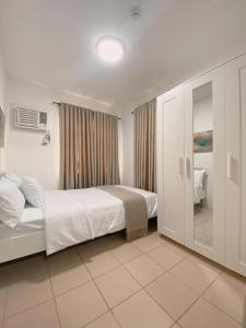 a white bedroom with a bed and a bathroom at AJA Suite in Davao City