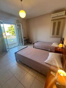a bedroom with two beds and a balcony at Villa Melissani in Karavomylos +5 photos
