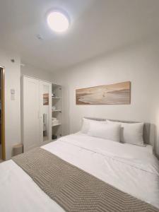 a white bedroom with a large white bed at AJA Suite in Davao City +2 photos