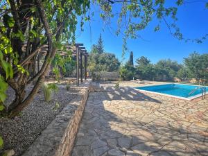 a garden with a swimming pool and a tree at Villa Melissani in Karavomylos