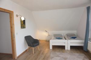 a bedroom with two beds and a chair in it at Doppelzimmer mit Bad in Möllenhagen