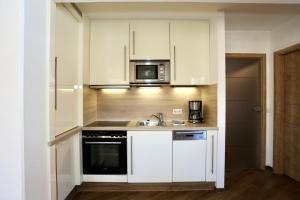 a kitchen with white cabinets and a sink and a microwave at Turmwohnung 205 in Juist