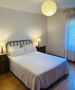 a bedroom with a large white bed with two night stands at Casa de la Tila in Arenas de Cabrales