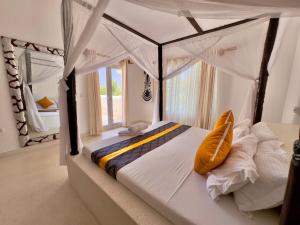 a bedroom with a white bed with a canopy at Villa Gladys in Watamu