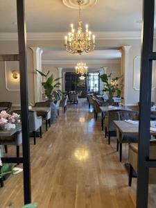 a dining room with tables and chairs and a chandelier at Kurhaus Bad Doberan in Bad Doberan