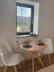 a dining room table with two chairs and a window at Maison Aline in Hotton
