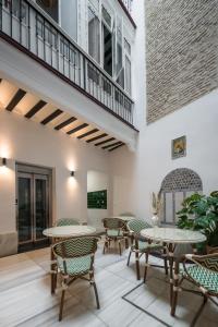a patio with tables and chairs and a balcony at Casa Tomás Boutique Hotel in Seville