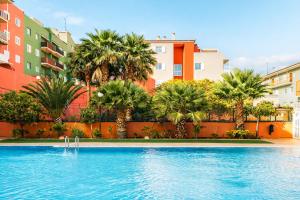 a swimming pool with palm trees in front of buildings at Profithome-Punta Larga in Candelaria