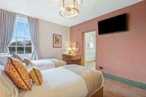 two beds in a hotel room with a flat screen tv at The Slow & Easy in Lostock Gralam