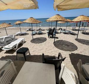 a beach with chairs and umbrellas and the ocean at mavikumsal otel in Kumburgaz