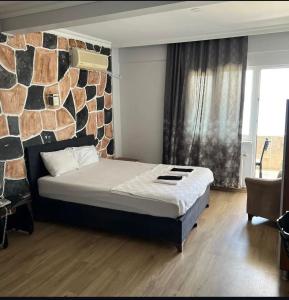a bedroom with a bed and a stone wall at mavikumsal otel in Kumburgaz