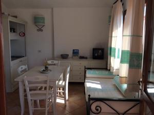 a room with a table and chairs and a kitchen at Sardinia Beach Apartments in Aglientu