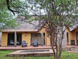 a yellow house with two chairs in front of it at Akasia - 333 in Hoedspruit