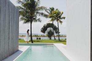 a woman in a white dress walking next to a swimming pool at KA BRU Beach Boutique Hotel in Barra Grande
