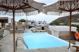 a swimming pool with umbrellas and a resort at Stone Apartments Kythnos in Kanala