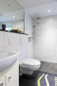a white bathroom with a toilet and a sink at Am Waldrand in Radis +8 photos