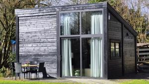 eine Hütte mit Glastüren, einem Tisch und Stühlen in der Unterkunft De Kansel in Nieuw-Dordrecht