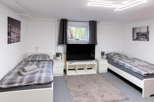a white room with two beds and a flat screen tv at Am Waldrand in Radis