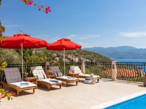 a patio with chairs and umbrellas next to a pool at VILLA SCARLETT in Kaş