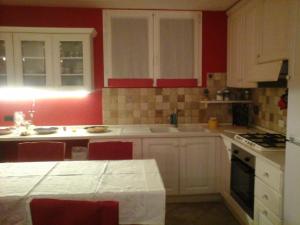 a kitchen with white cabinets and red walls at Casa Olimpia - Mareri apartments in Poggi