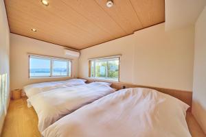 two beds in a room with two windows at プライベートリゾート清風 in Atami