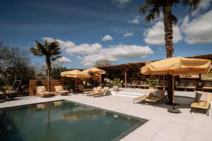 a swimming pool with umbrellas and lounge chairs and a pool at Herdade dos Moreiros in Arronches