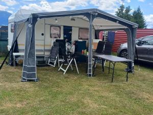 a camper with a table and chairs under a tent at Camping Dorfer in Spielberg