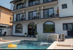 a house with a swimming pool in front of a building at Mala House in Orşova