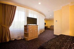 a hotel room with a television on a dresser with a window at GRAND OTRADA Hotel Resort & SPA in Odesa