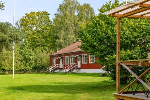 a small red house in a field with a yard at Haraldsgården Vandrarhem in Blidö