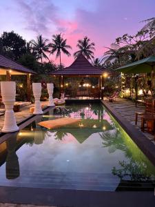 a pool in front of a house with a sunset at Villa Padi Cangkringan in Sleman